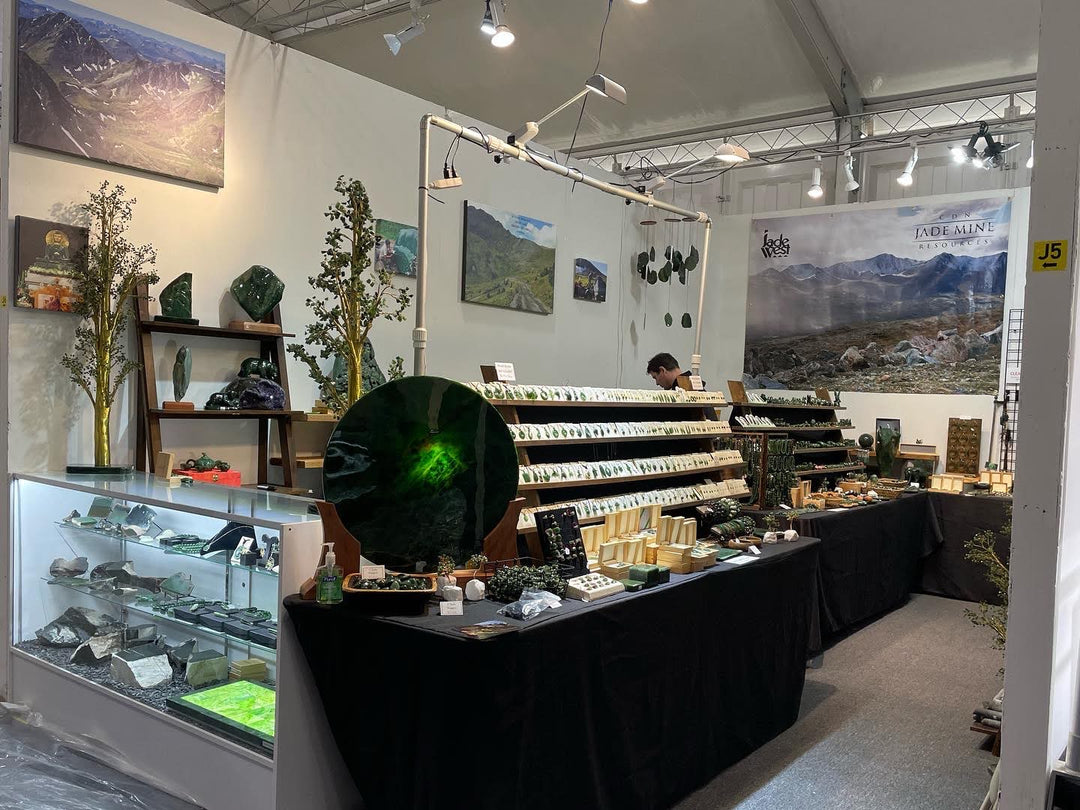 Jade Mine Resources booth at a gem show with jade displays and a large mountain banner