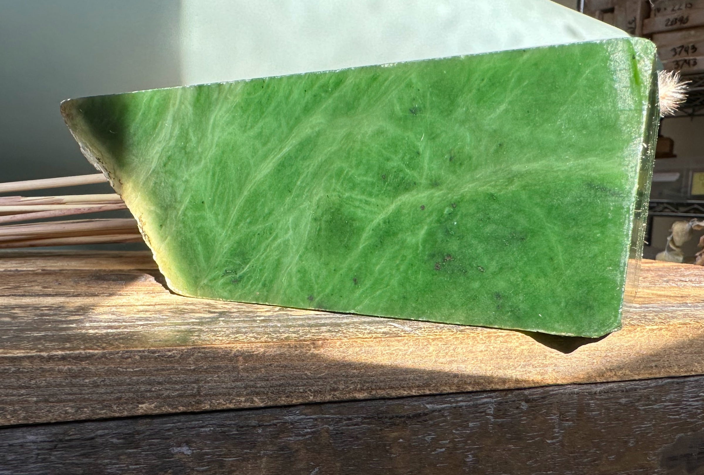 Large slab of green Canadian rough jade resting on a wooden surface