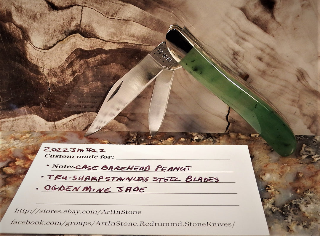 Ogden Jade Knife by Michael Hoover with green jade handle and two blades opened across a woodgrain and stone backdrop.