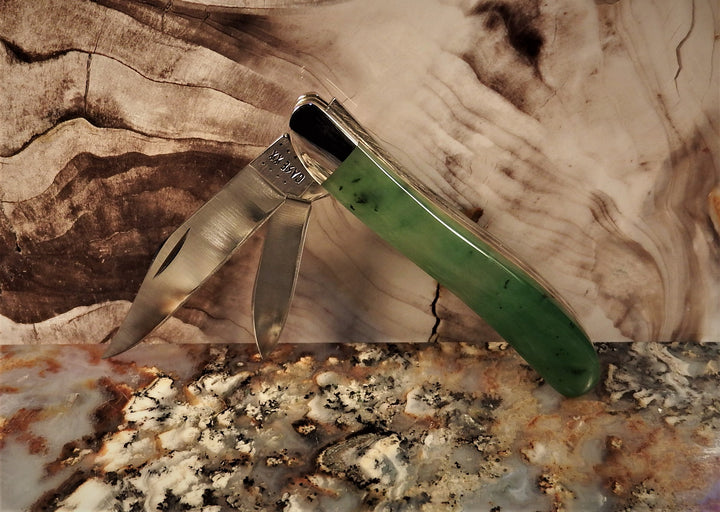 Ogden Jade Knife by Michael Hoover with a green jade handle and several blades fanned open against a marble backdrop
