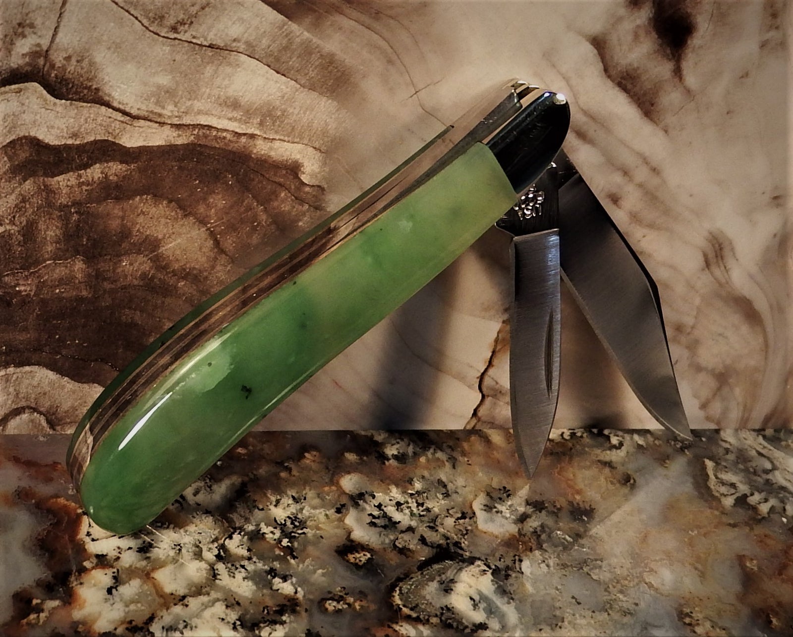 Ogden Jade Knife by Michael Hoover with green jade handle and multiple blades extended against a marbled stone backdrop.