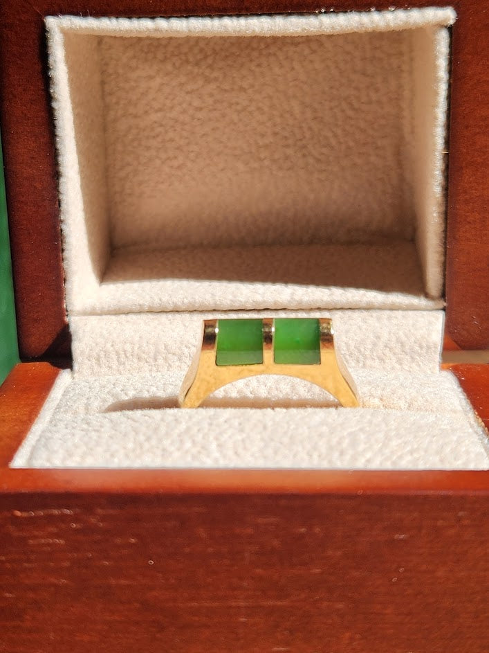 Vintage jade ring with two green rectangular stones set in gold, displayed in a white padded jewelry box.