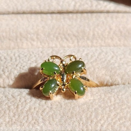 Butterfly shaped Vintage Jade Ring with four green jade stones in a gold setting on pale fabric