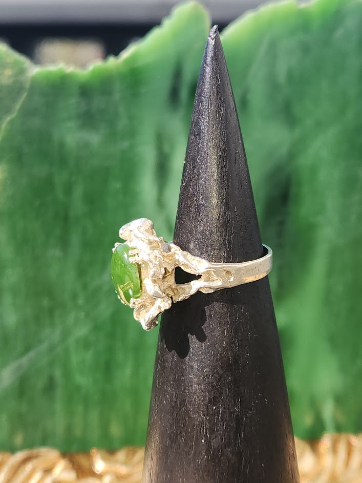 Green jade cabochon ring with ornate gold Medusa inspired cluster on a black display cone