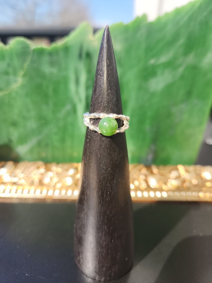 Green jade ring with grooved silver double band displayed on a black ring stand