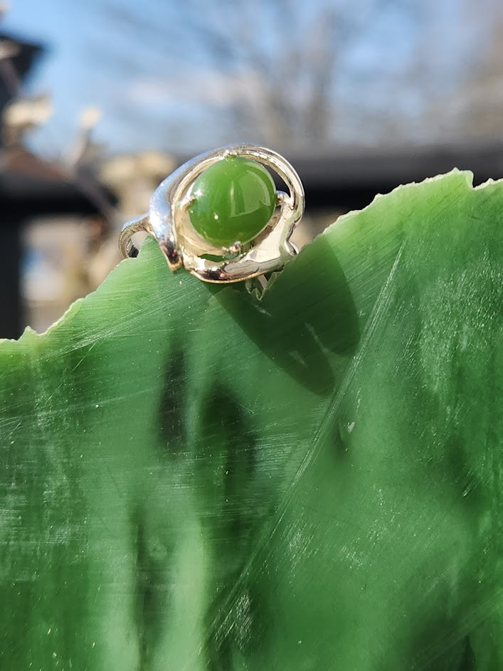 Silver Jade Ring with green jade cabochon resting on a large leaf outdoors