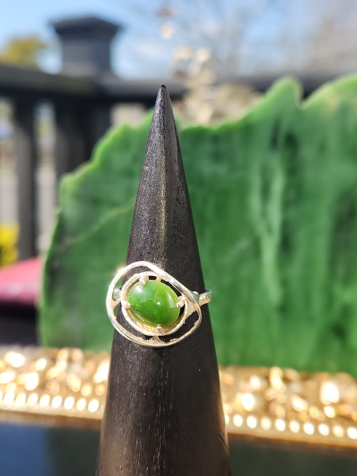 Silver Jade Ring with a green jade cabochon in a circular silver setting on a black cone display.