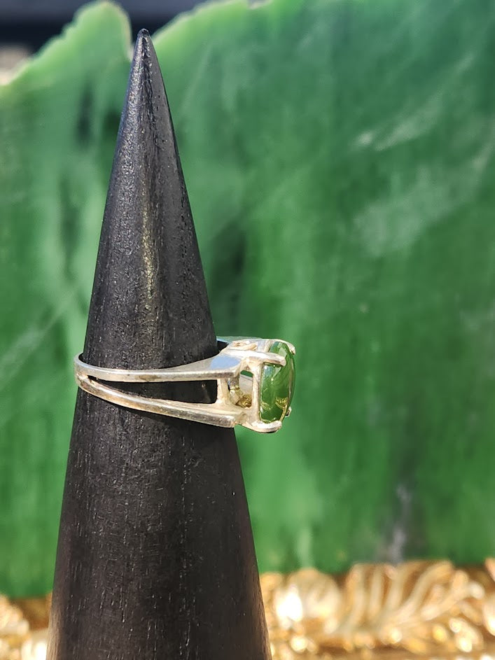 Jade ring with a green stone displayed on a black cone stand