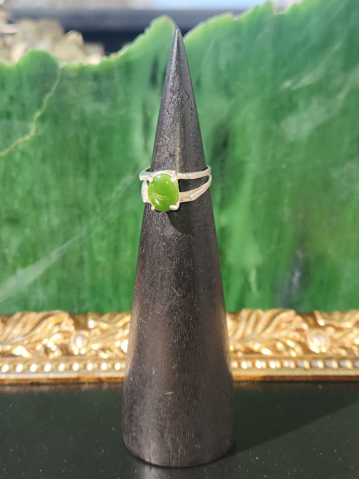 Side view of the silver jade ring on a black cone against a green backdrop