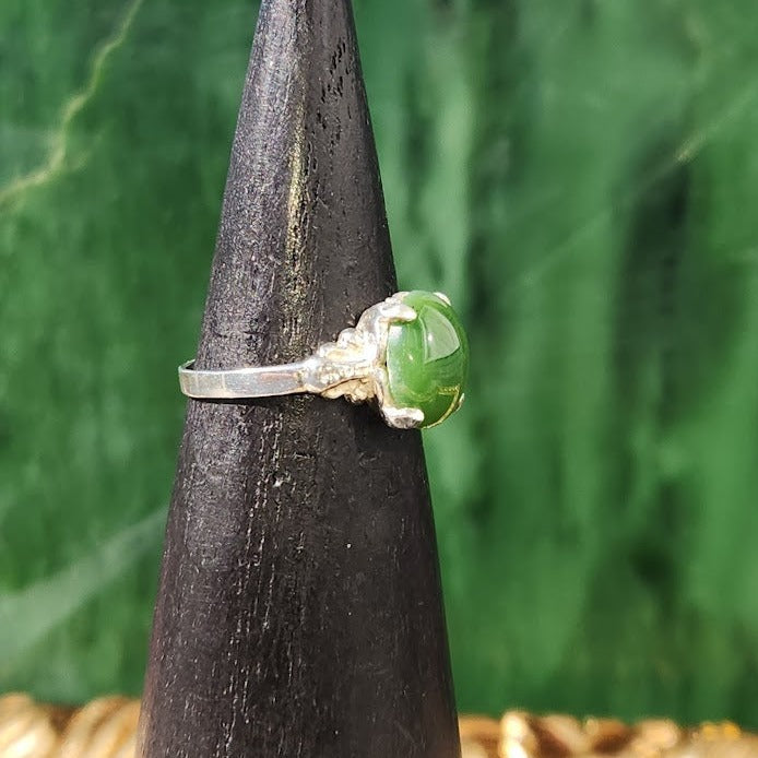 Canadian Jade Ring displayed on a ring cone from the side with green jade centerpiece and decorative silver band.