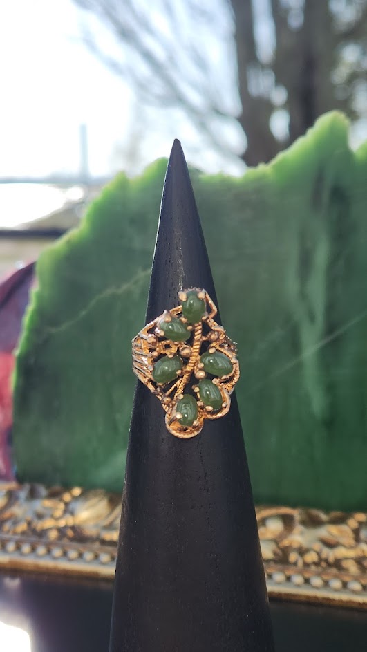 Side view of Vintage Jade Ring with green jade beads and intricate gold setting on a black display cone.
