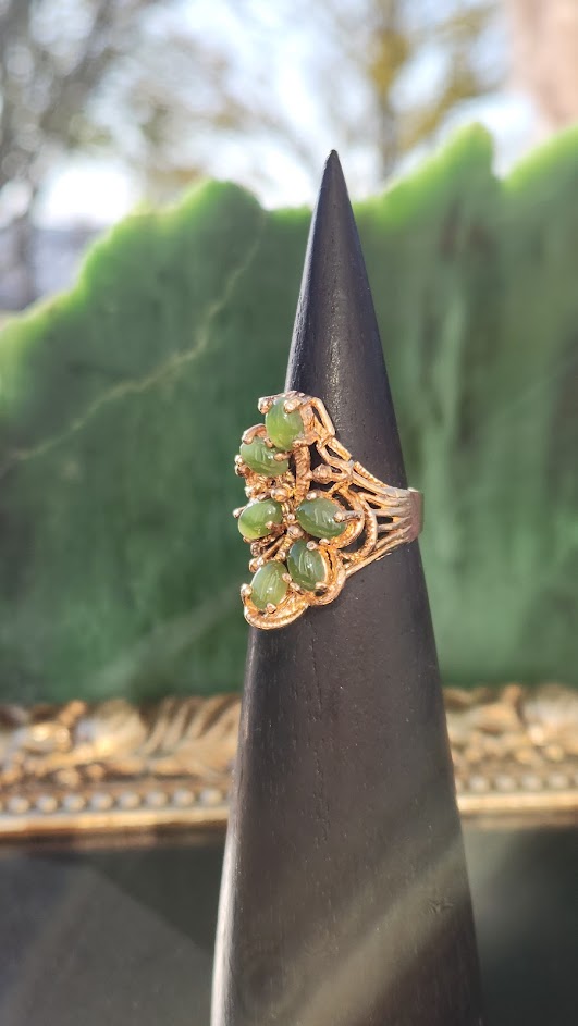 Vintage Jade Ring on a black display cone with a soft outdoor backdrop.