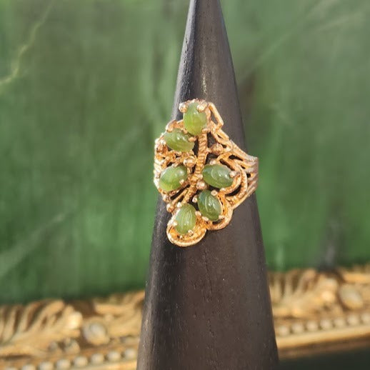 Close-up of Vintage Jade Ring with green jade beads in an ornate gold setting on a black display cone.