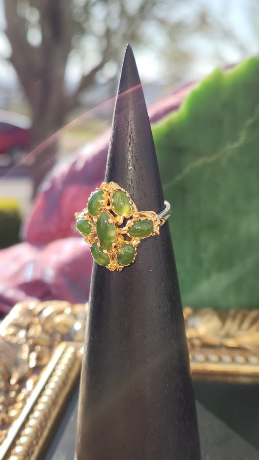 Close-up of Vintage Jade Ring showcasing a gold floral cluster of green jade stones on a slender black cone.