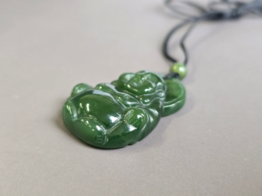 Front-facing green jade Laughing Buddha pendant on a black cord with a matching green bead, shown at an angle