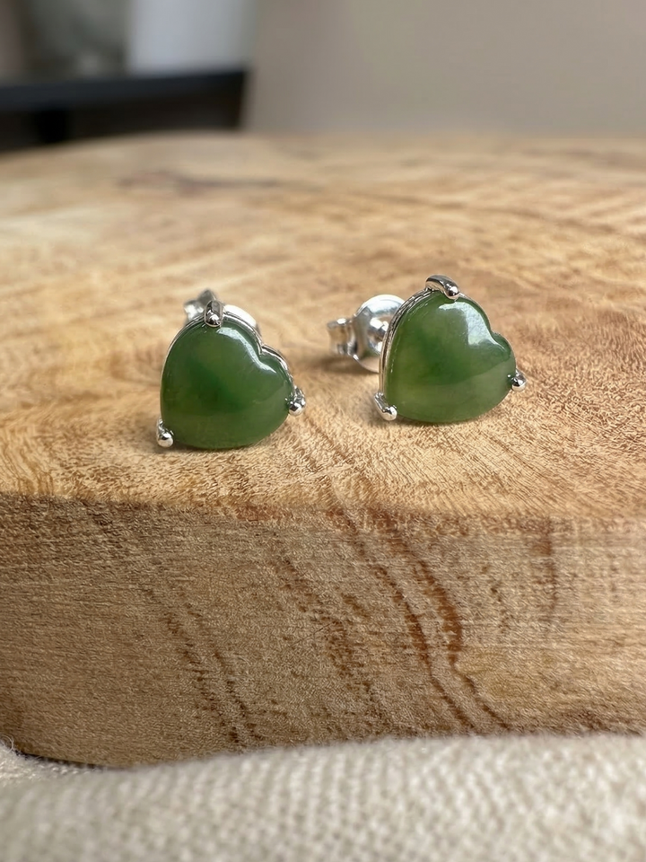 Silver heart shaped earrings with green jade stones set in prongs.