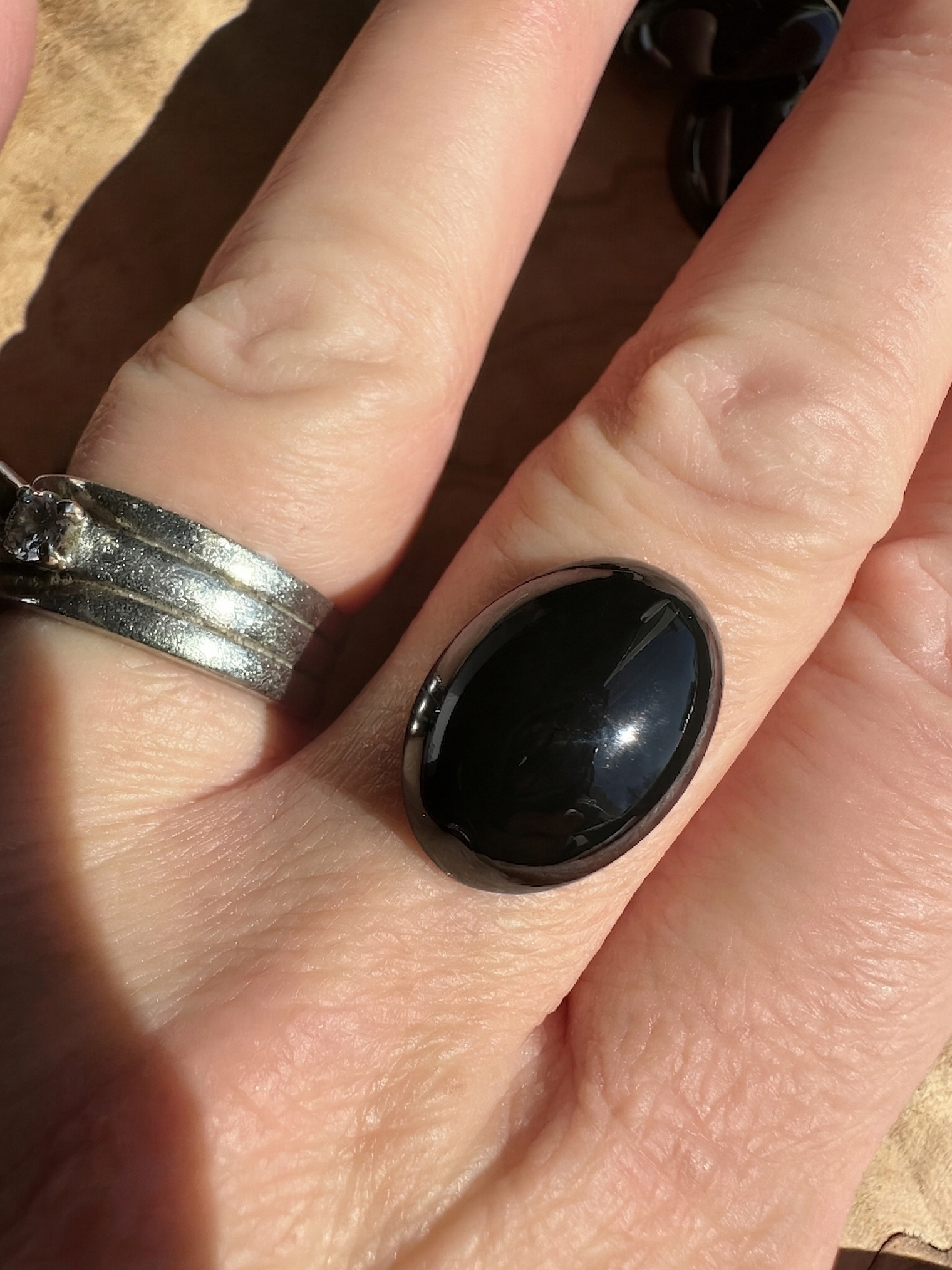 Large polished oval black Jade cabochon set in a silver ring worn on a finger