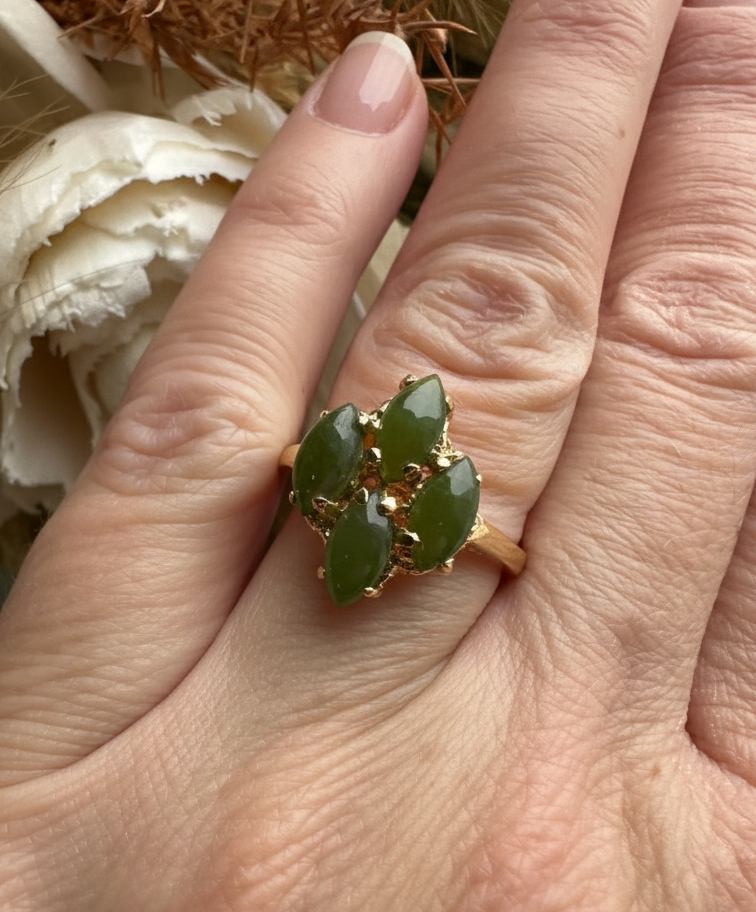 Vintage Canadian green jade ring on finger featuring a four stone leaf cluster in a gold setting