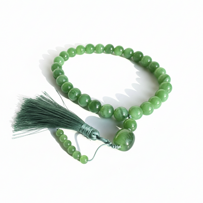 Green Siberian jade beaded prayer bracelet with tassel on a white background