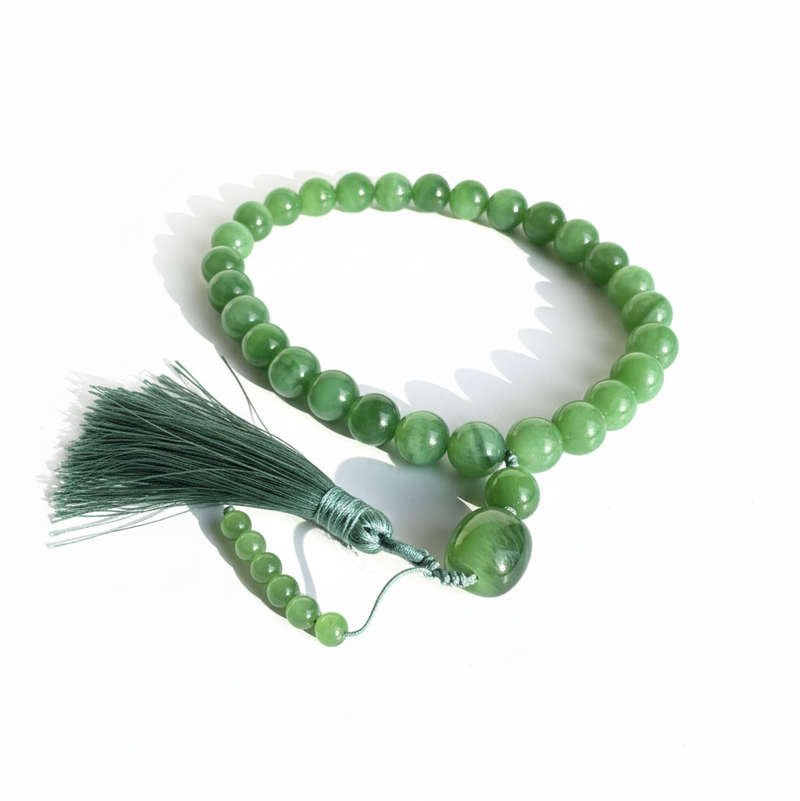 Green Siberian jade beaded prayer bracelet with tassel on a white background