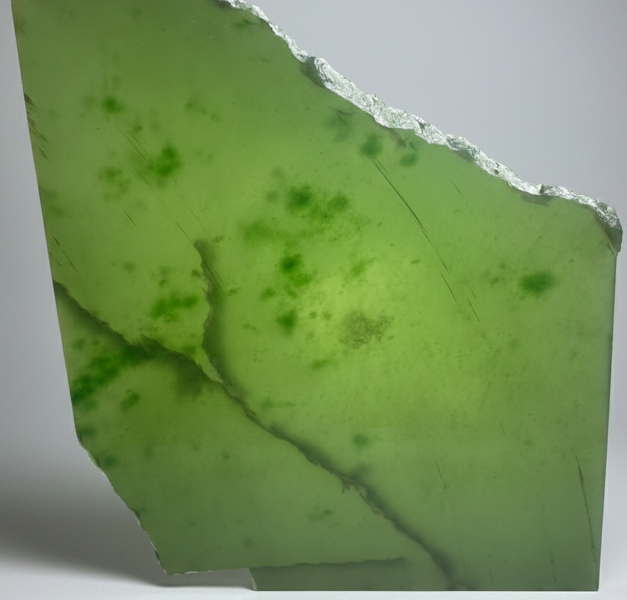 A+ Siberian Nephrite jade slab in bright lime green with a rough jagged top edge and visible cracks
