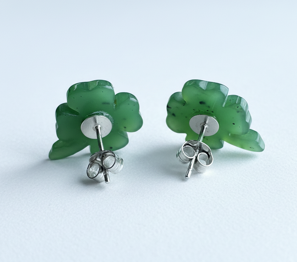 Pair of green clover-shaped earrings on a light blue background