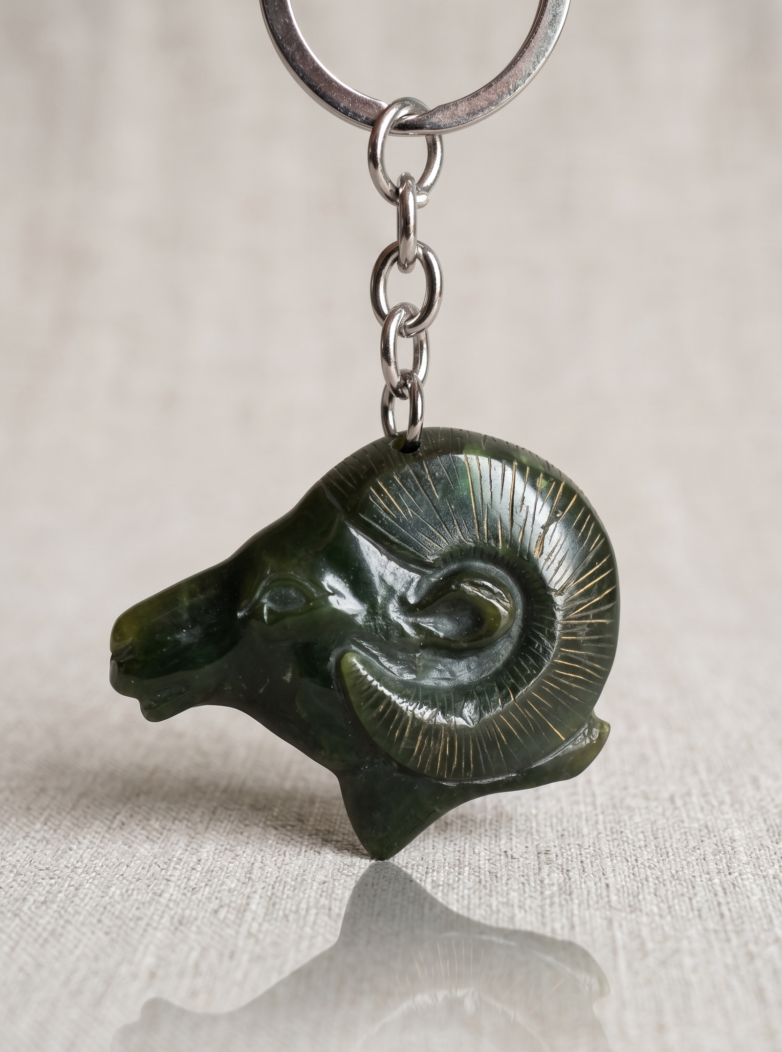 Keychain with a green stone ram head pendant on a light background