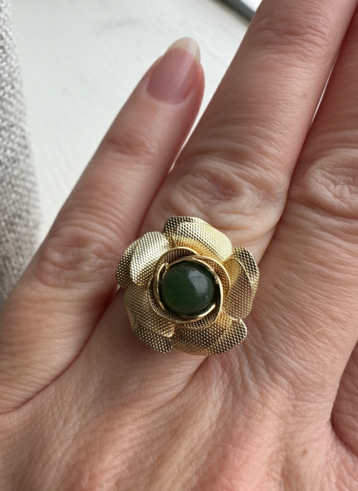 Gold ring with a green gemstone on a hand