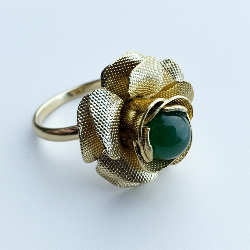 Side view of a vintage gold tone rose ring with a green jade centerpiece and an adjustable band.
