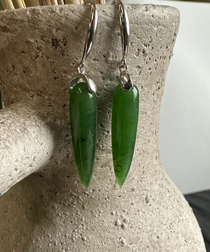 Close up of Canadian Jade Earrings JN3 green jade drops with silver caps and hooks on a display stand