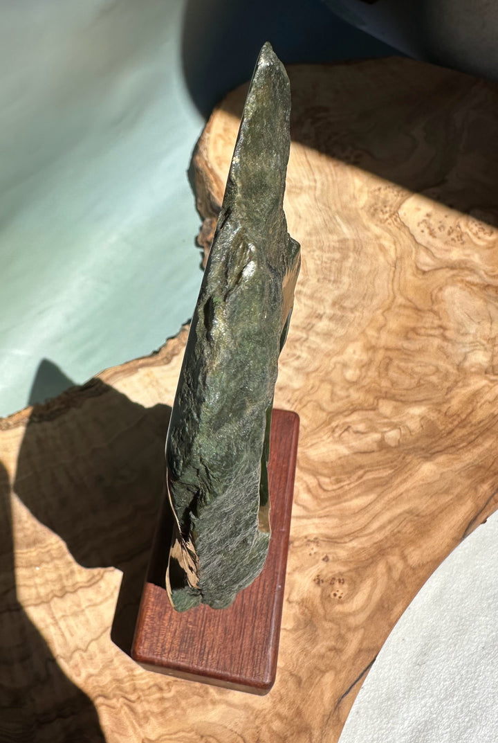 Side view of Canadian Jade Double Koru Sculpture showing a tall rough green jade shard mounted on a wooden base.