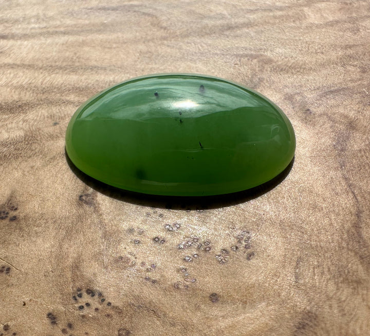 AA Siberian Apple Green Cabochon 30x22mm glossy oval gemstone on a wooden surface