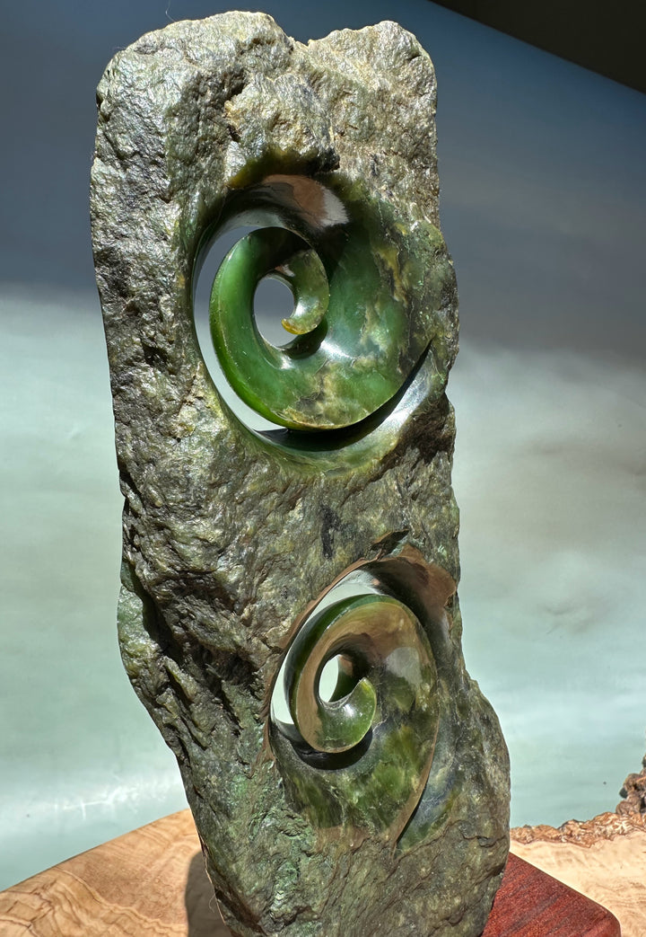 Canadian Jade Double Koru Sculpture eight inches tall with two emerald green spirals set in a rugged rock base.