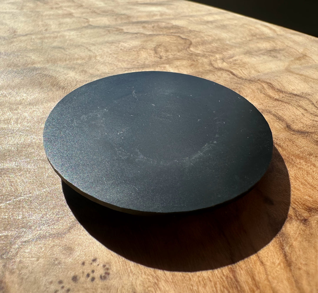 back side of Black round jade on a wooden surface