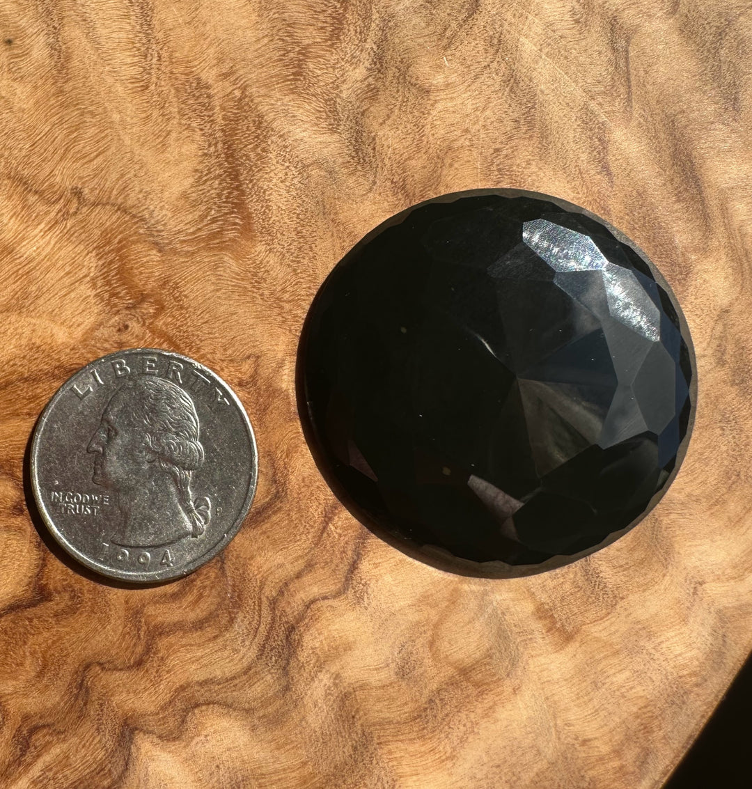 Black jade next to a U.S. quarter on a wooden surface