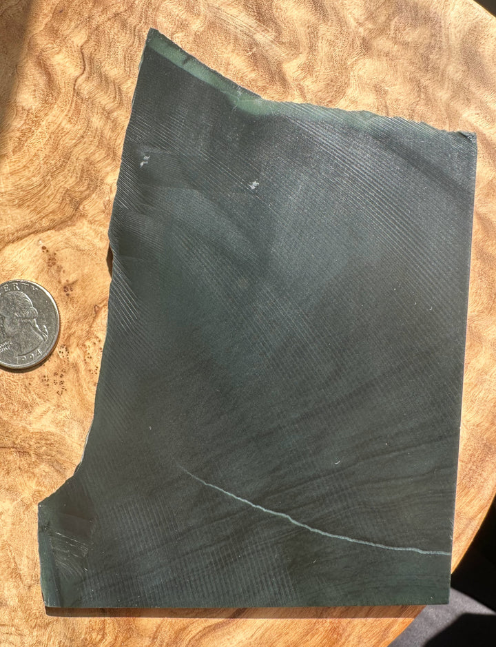 jade stone on a wooden surface with a coin for scale