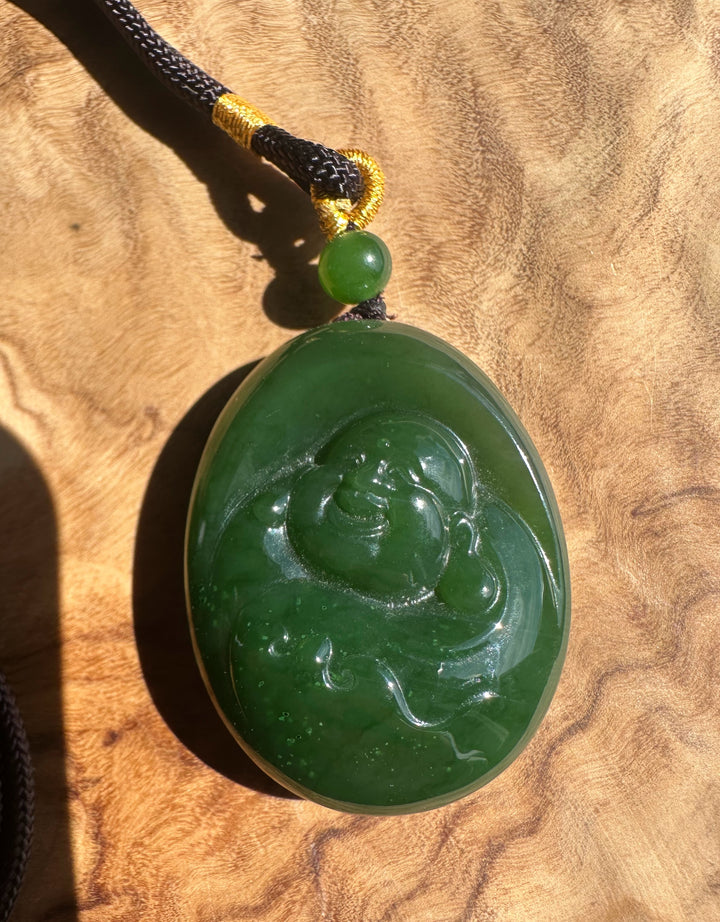 Green jade pendant with Buddha carving on a wooden surface