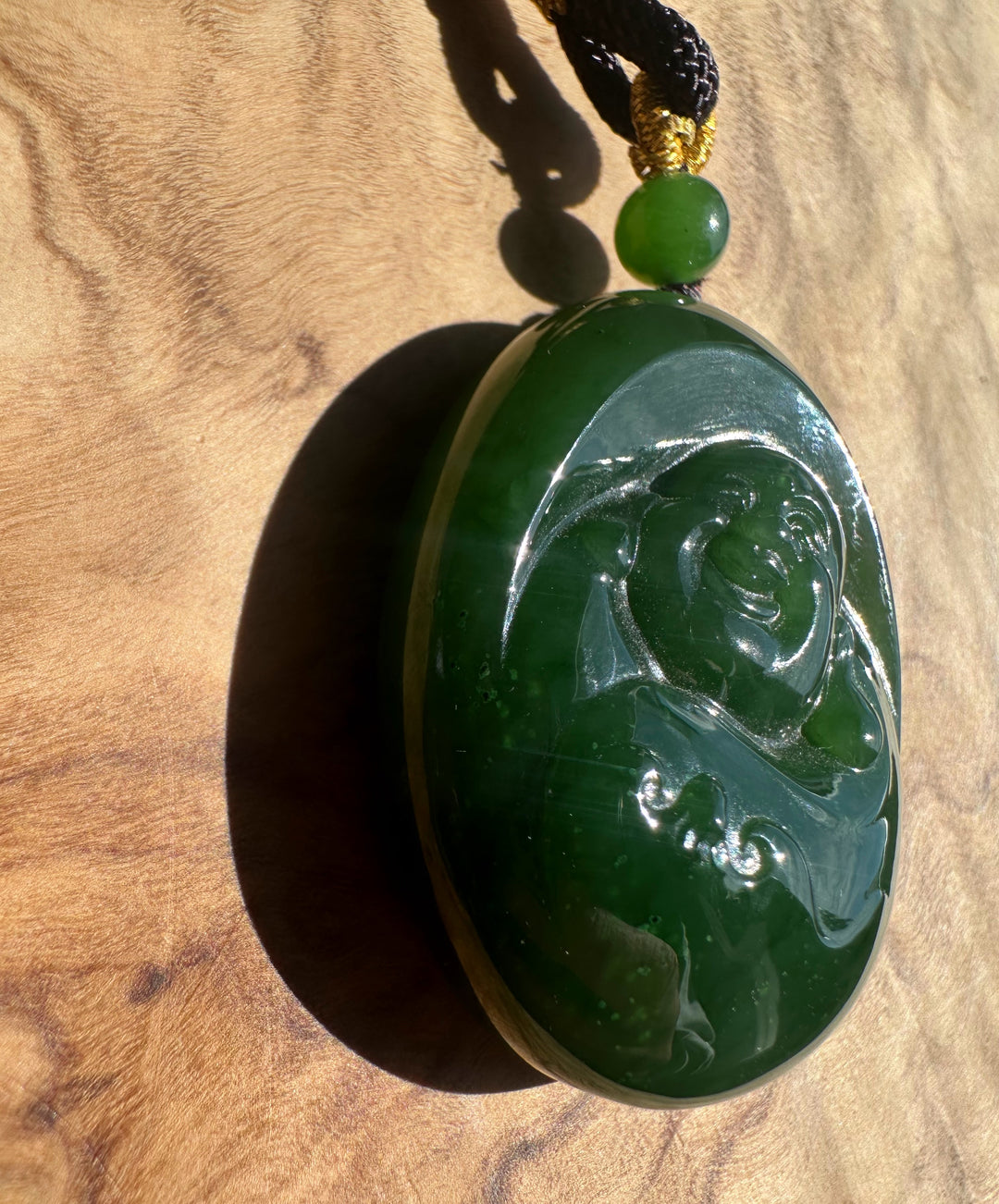 Green jade pendant with intricate carvings on a wooden surface