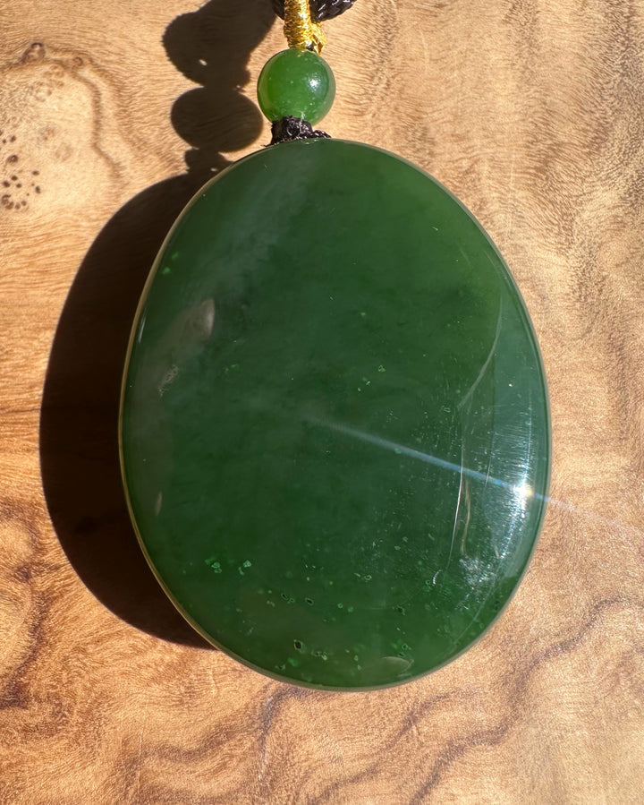 Green jade pendant on a wooden surface