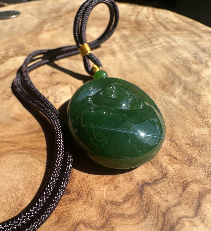 Green jade pendant on a brown cord on a wooden surface