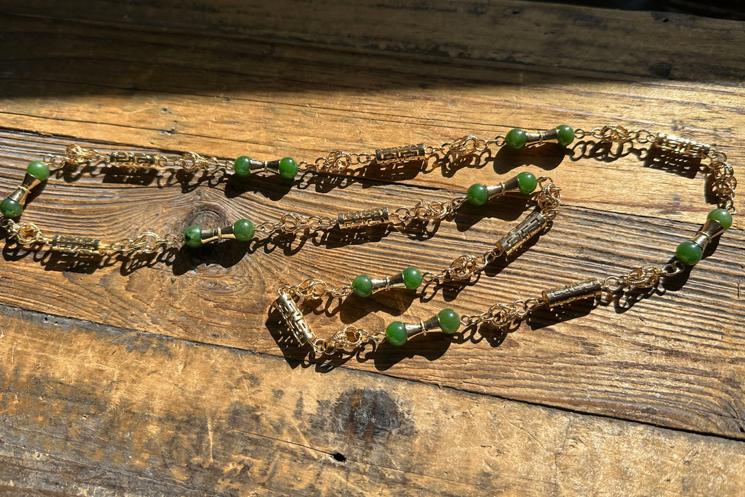 Vintage Jade Necklace 30 inch with gold chain and green beads laid on a rustic wooden surface.