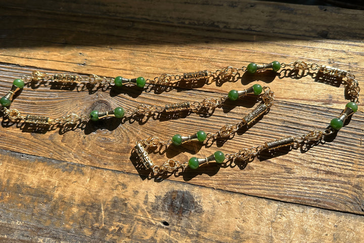 Vintage Jade Necklace 30 inch with gold chain and green beads laid on a rustic wooden surface.