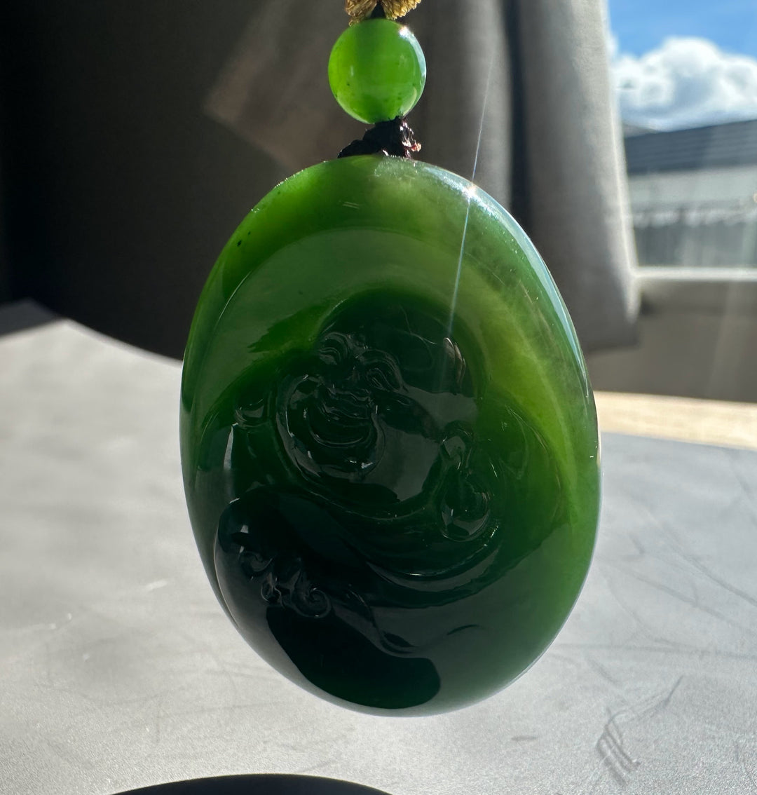 Green jade pendant with intricate design on a neutral background