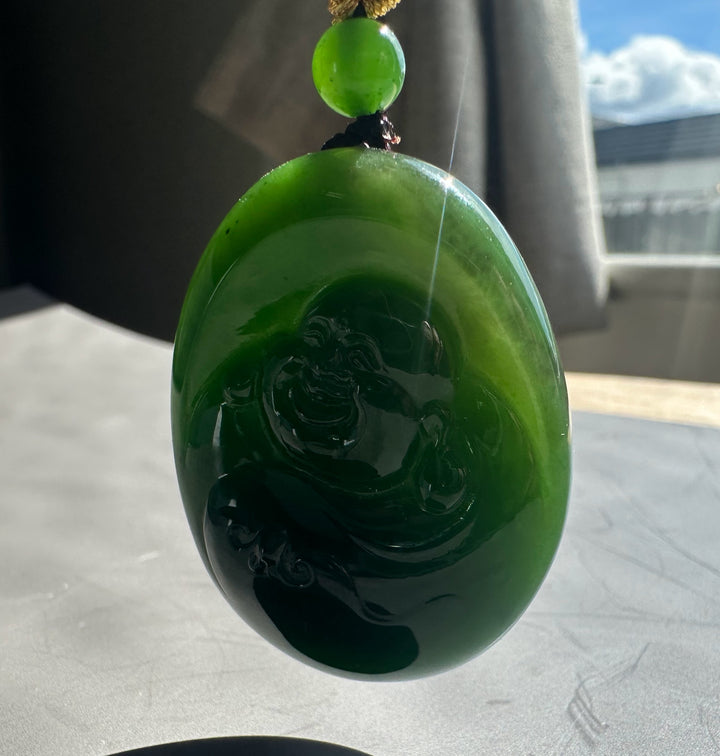 Green jade pendant with intricate design on a neutral background