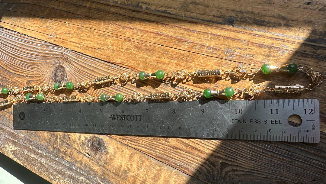 Close up of Vintage Jade Necklace 30 inch with green beads and gold links beside a ruler for scale.