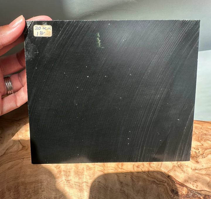 Person holds a Wyoming Jade Slab with a small corner label noting size and weight.