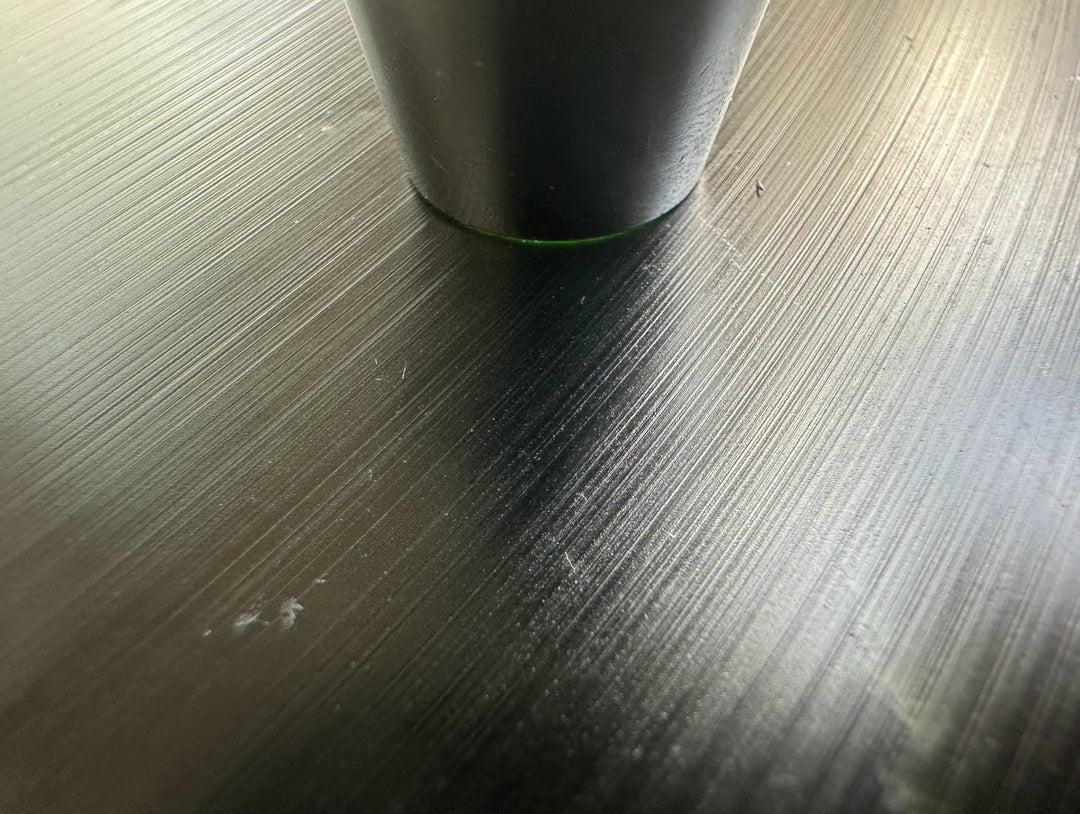 Close up of Wyoming Jade Slab surface showing fine brushed lines with a cylindrical object resting on top.