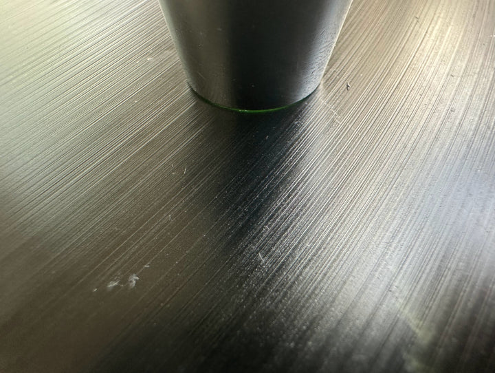 Close up of Wyoming Jade Slab surface showing fine brushed lines with a cylindrical object resting on top.