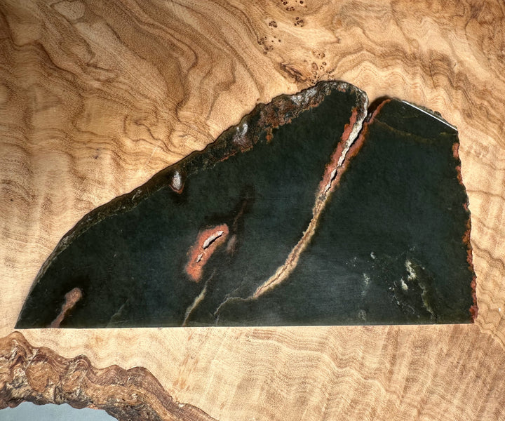 Wyoming Jade Slab 105g with dark green surface and reddish veins on a wooden background