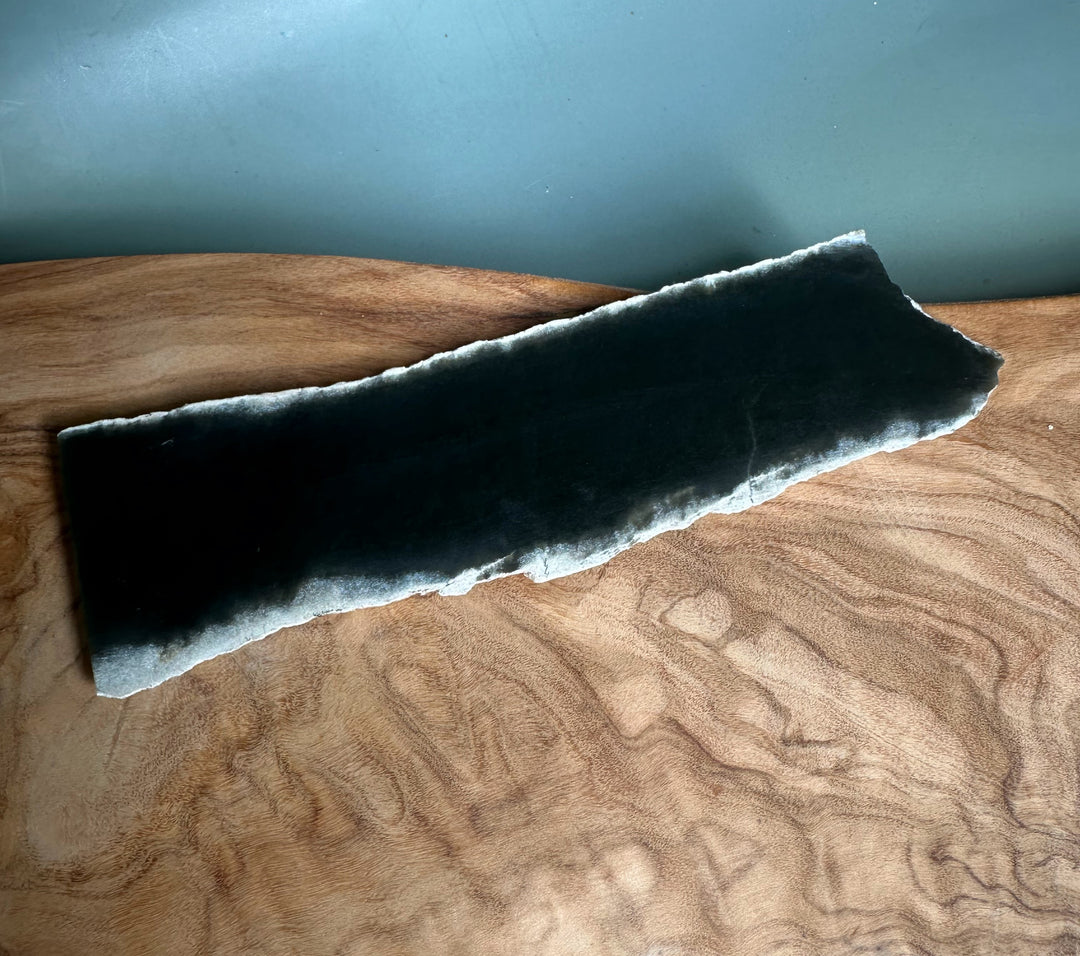 Wyoming Slab 50g narrow dark blue black slab with pale frosted edge resting on a wooden surface.